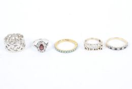 A collection of five silver and yellow metal rings.