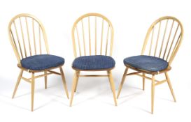 A set of three blonde Ercol dining chairs.