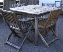 A teak garden table and four folding chairs. The table of square section, 92.