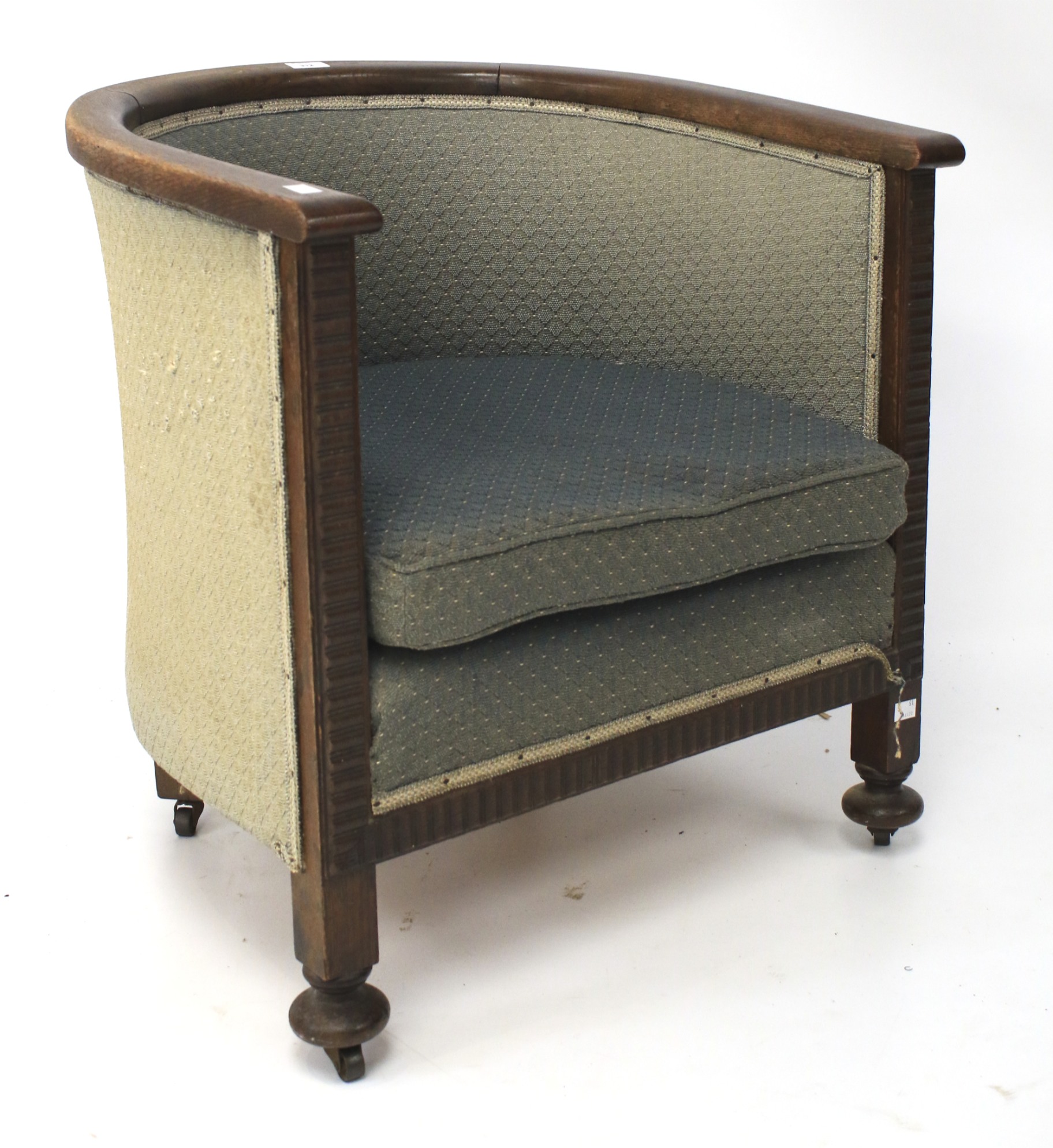 An Arts and Crafts style oak tub chair. With reeded frame, raised on squat bun supports to casters.