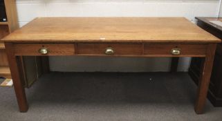 A mid-century oak table on square supports with three drawers to front. L 182cm x D 89cm x H 76cm.