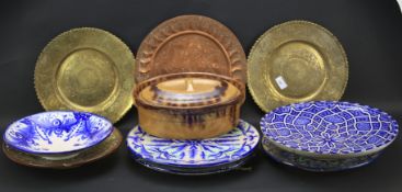 An assortment of ceramic and brass plates.