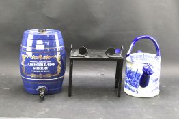An Amontillado Sherry ceramic cask, a blue and white decorative watering can and a metal stand