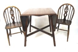 An oak Ercol drop leaf table and two chairs.