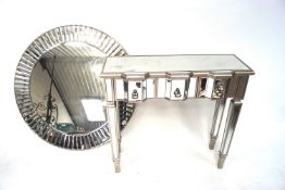 A contemporary chrome mirrored dressing table together with a similar wall mirror.