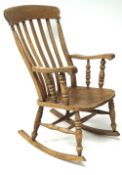 A pine widsor rocking chair. with turned arm suppots and turned supports united by sretchers.