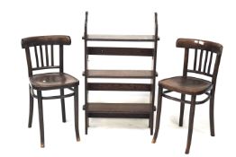 Two stained bentwood chairs and a stained oak bookshelf.