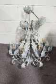 A large ornate eight arm ceiling chandelier. Decorated with leaves, painted pale grey.