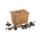 A square wicker basket containing fishing equipment. Including reels, hooks, floats, etc.