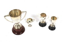 Three silver sporting trophies and a silver-plated trophy.