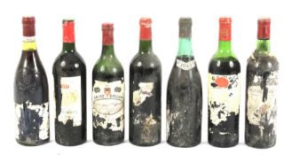Seven bottles of vintage red wine.