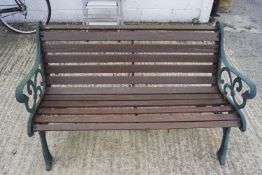 A wooden garden bench. With green painted metal end supports.