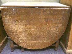 An oak gateleg table. Of oval form, raised on turned supports.