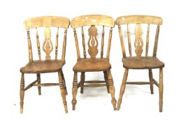 A set of three elm kitchen chairs. All with pierced back splat, raised on turned supports.