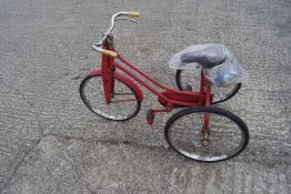 A red painted child's tricycle. With separate original saddle.