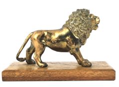 An early 20th century brass model of a lion on wooden stand mounted as a paperweight.