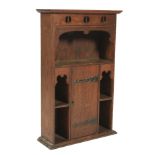 An oak Liberty style hanging bookcase. With pierced decoration to the pelmit above a shaped shelf.