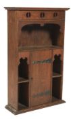 An oak Liberty style hanging bookcase. With pierced decoration to the pelmit above a shaped shelf.