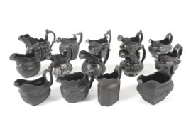 A collection of early-mid 19th century fourteen British black basalt and Jackfield-type milk-jugs.