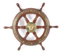 A six-spoke mahogany and brass ship's wheel. Maker Simpson Lawrence, diameter 61cm.