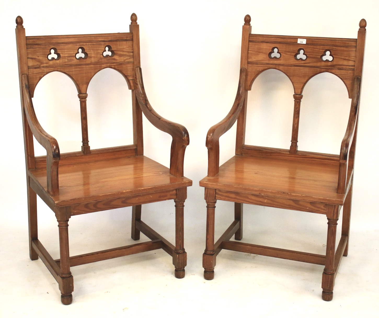 A pair of pitch pine ecclesiastical elbow altar chairs.