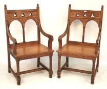 A pair of pitch pine ecclesiastical elbow altar chairs.