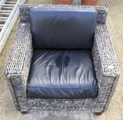 A contemporary wicker armchair with cushions.