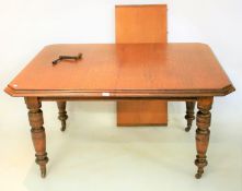 An Edwardian oak wind out dining table with extra leaf.