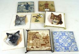 A collection of ceramic wall tiles. Including tiles depicting cats.