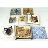 A collection of ceramic wall tiles. Including tiles depicting cats.