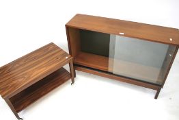 A teak sideboard with sliding glass doors and a two tiered push along trolley.