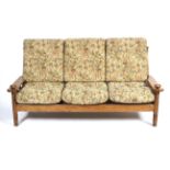 A three piece oak suite of a three-seater sofa and two armchairs.