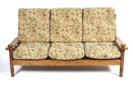 A three piece oak suite of a three-seater sofa and two armchairs.