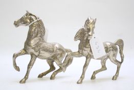 A pair of white metal horses in a prancing pose,