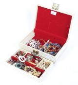 An assortment of costume jewellery and beads in a cream jewellery box.