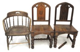A pair of early 20th century oak hall chairs with armorial carvings and a tub chair.