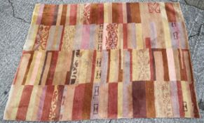 A 20th century rug woven. In abstract patterns on stripped pink, red and beige bands. 171cm x 236.