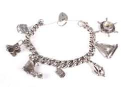 A white metal curb link charm bracelet and charms. On a padlock clasp stamped 'Silver'.