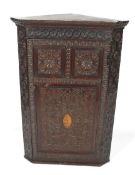 An early 20th century carved and stained oak corner cupboard.