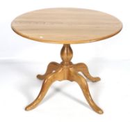An Ercol round elm table on quadripartite cabriole support.