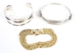 Two silver bangles and a five strand silver gilt bracelet.