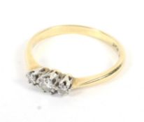 An 18ct gold and platinum set three stone diamond ring. Size R, weight 2.6 grams.