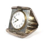 A silver cased travelling bedside clock with engine turned decoration to the case.