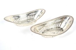 A pair of silver dishes, of oval form. With gadroon decorated rim and the body with.