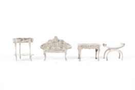 Four assorted miniature silver pieces of furniture.