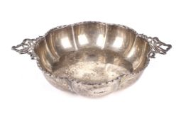 A silver ribbed, twin handled porringer.