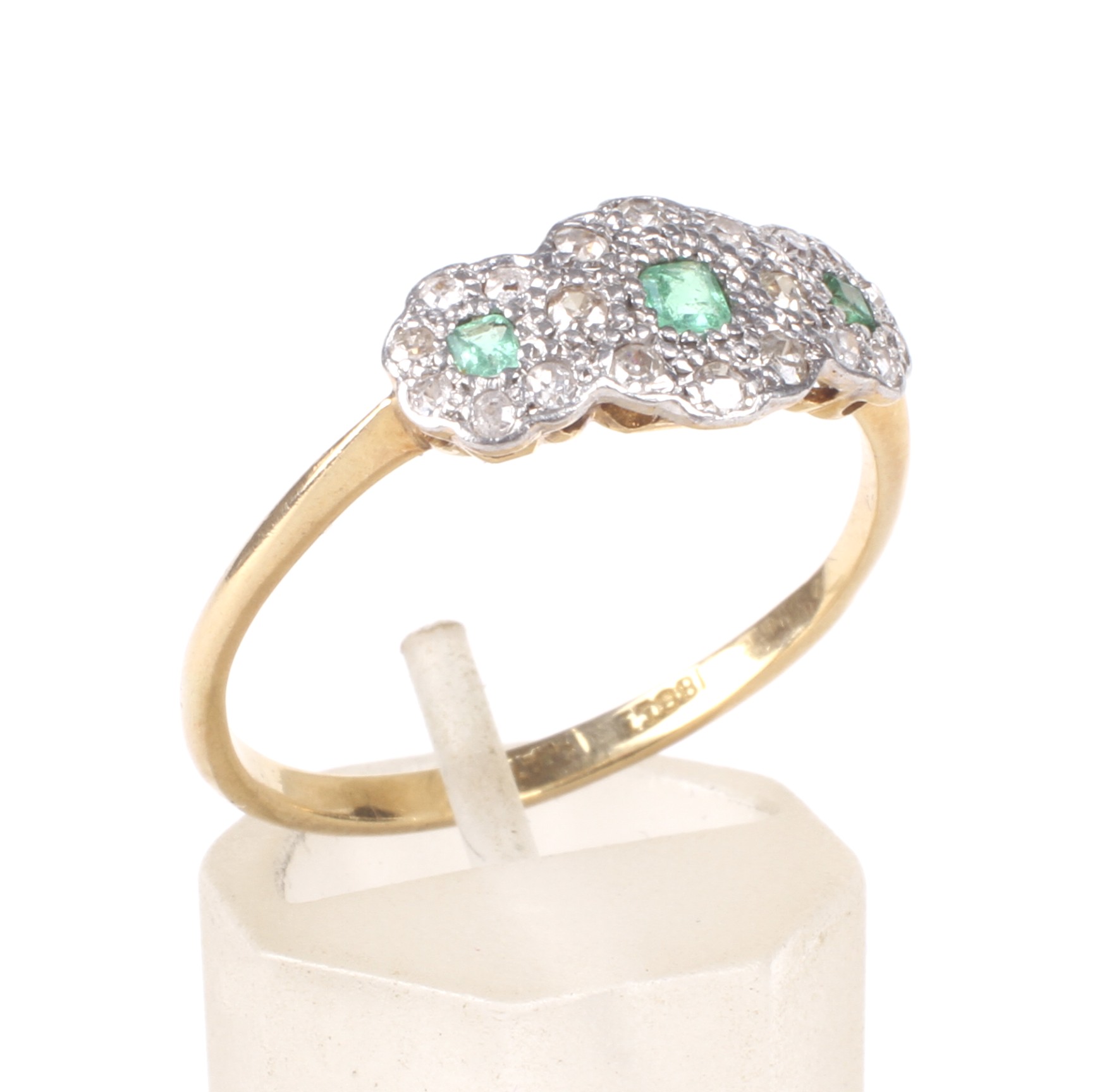 An early 20th century gold, emerald and diamond triple-cluster ring, circa 1930.