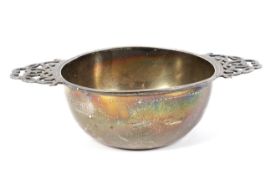 A silver porringer with pierced decorated handles.