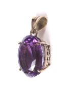 A vintage yellow metal and amethyst pendant. The oval native-cut stone approx. 16.