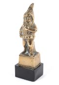 A polished gilt-bronze car mascot of a gnome. Cast standing, on black base, 14.